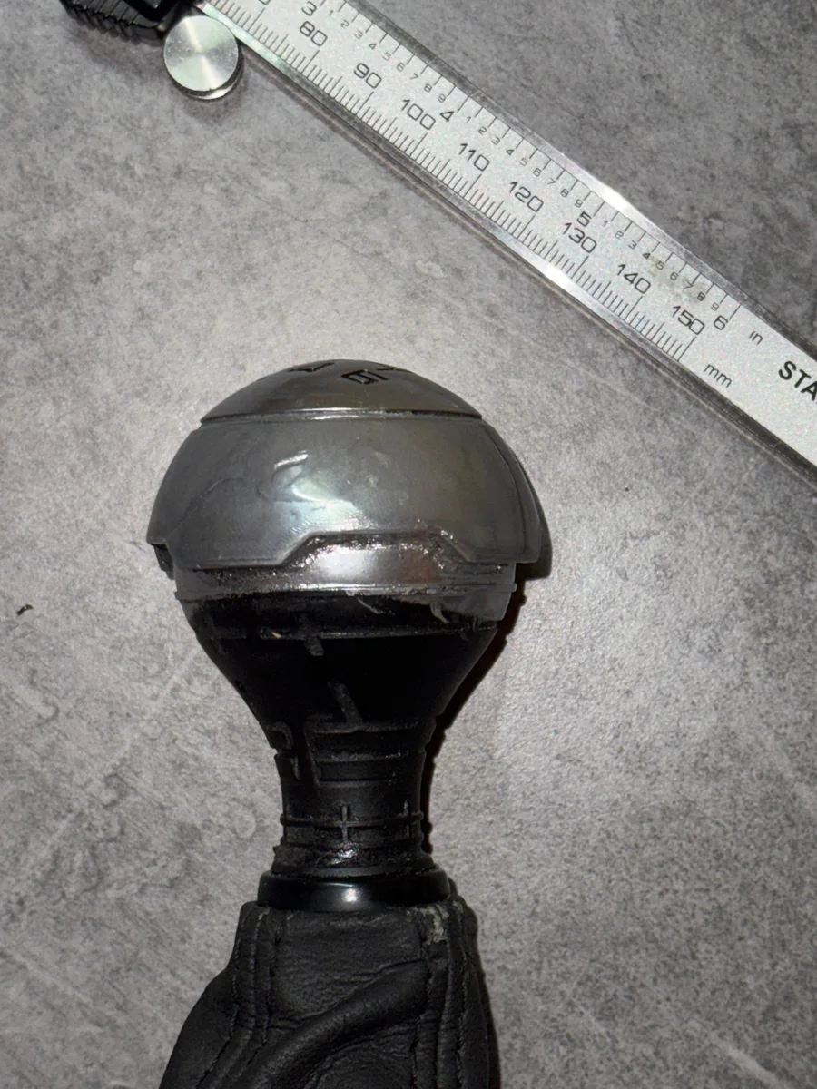 The original knob with the lower grip melted away, next to a caliper